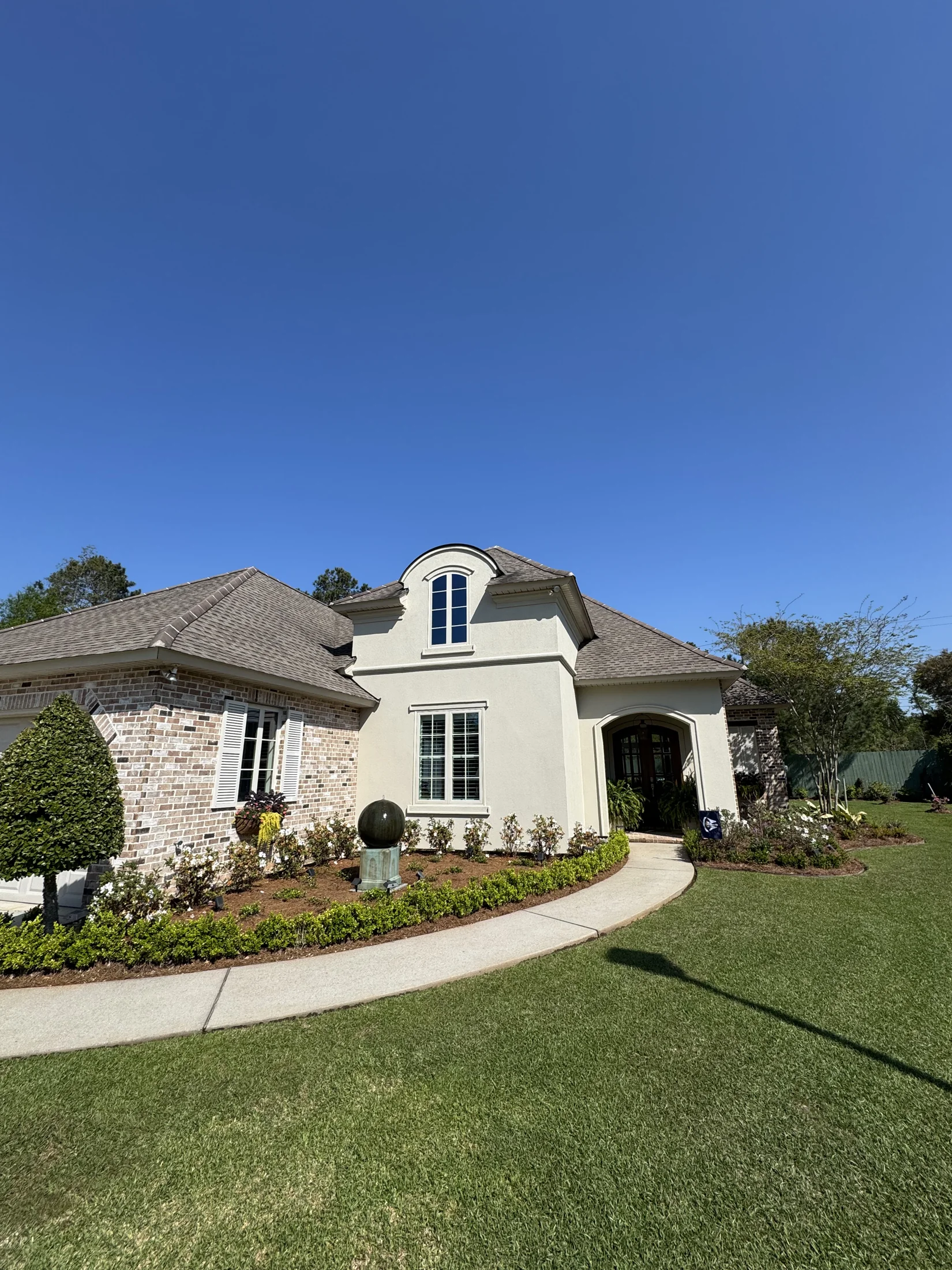 Painted stucco and brick home with white shutters and arched entryway in the New Orleans metro area