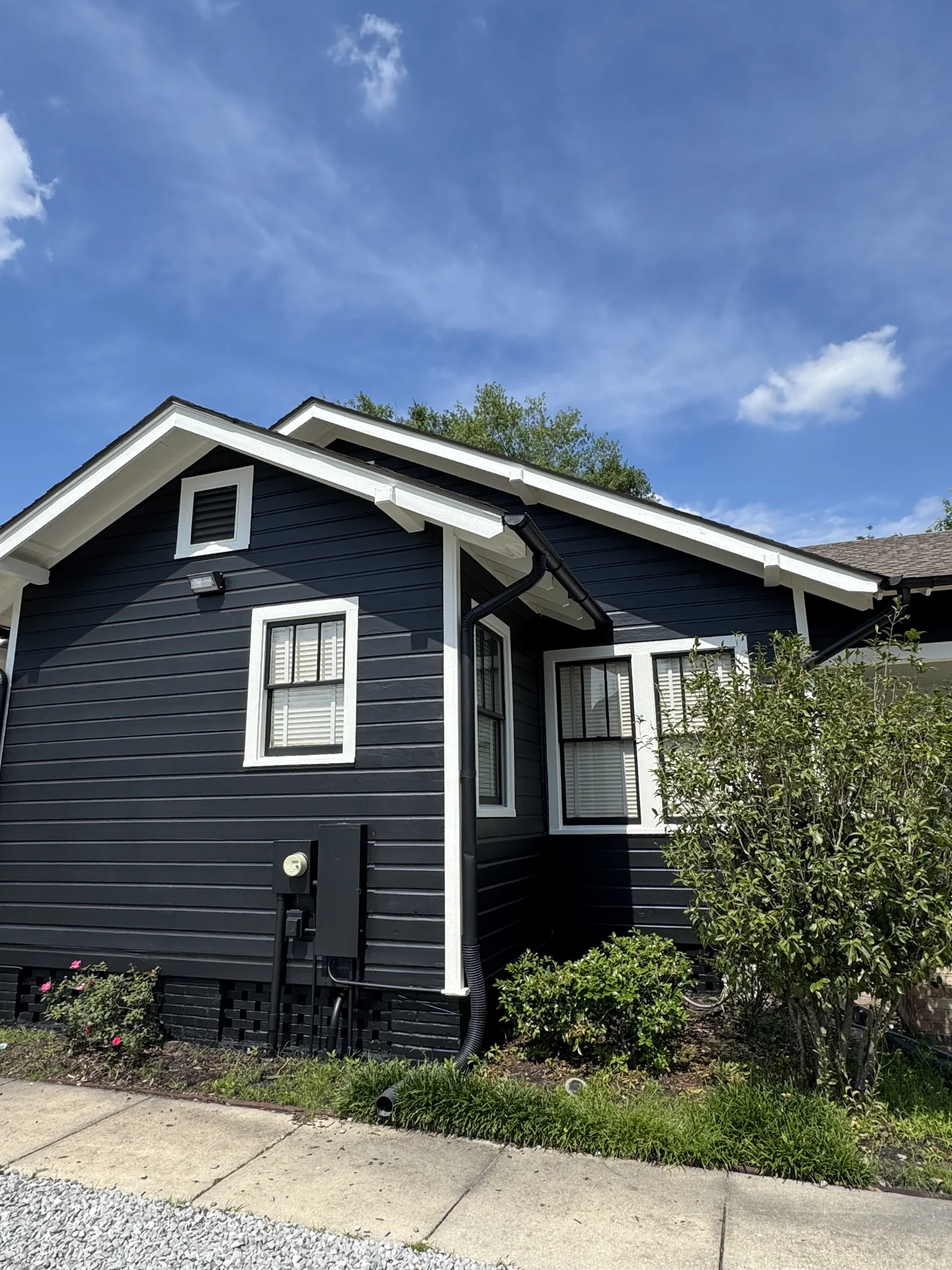 New Orleans bungalow painted dark navy with white trim, eaves, and window frames
